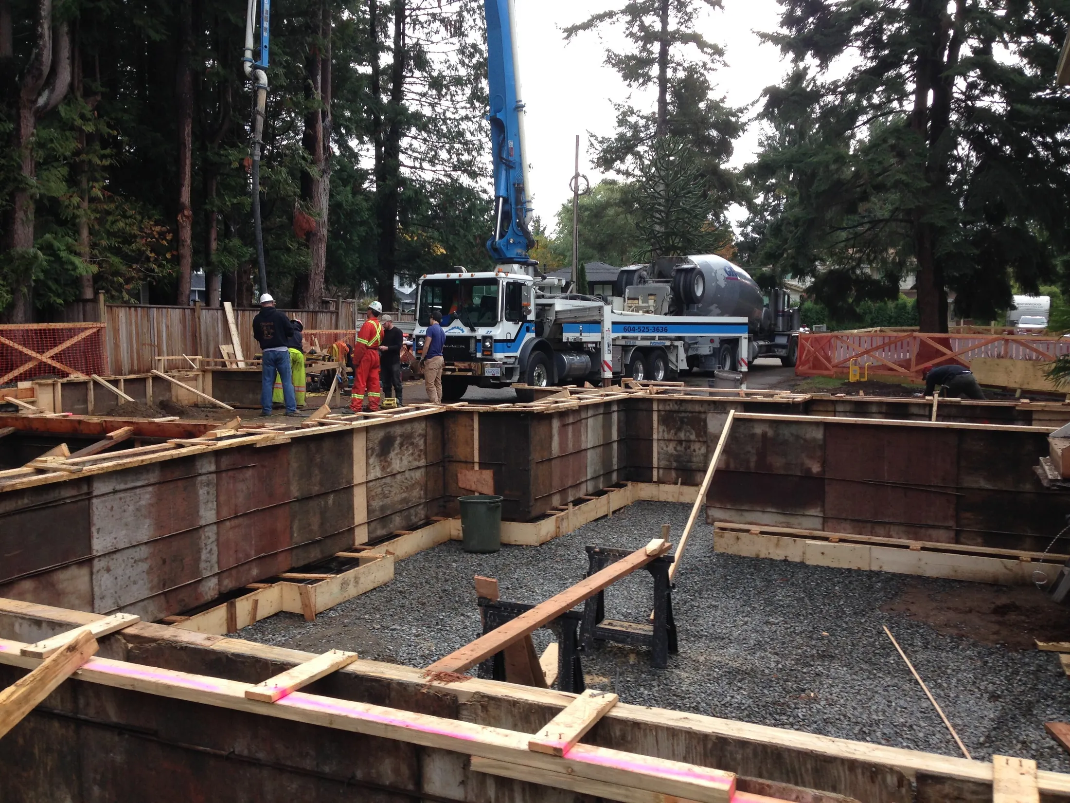 Foundation stage: concrete forms being poured with a pump truck and mixer truck on site.