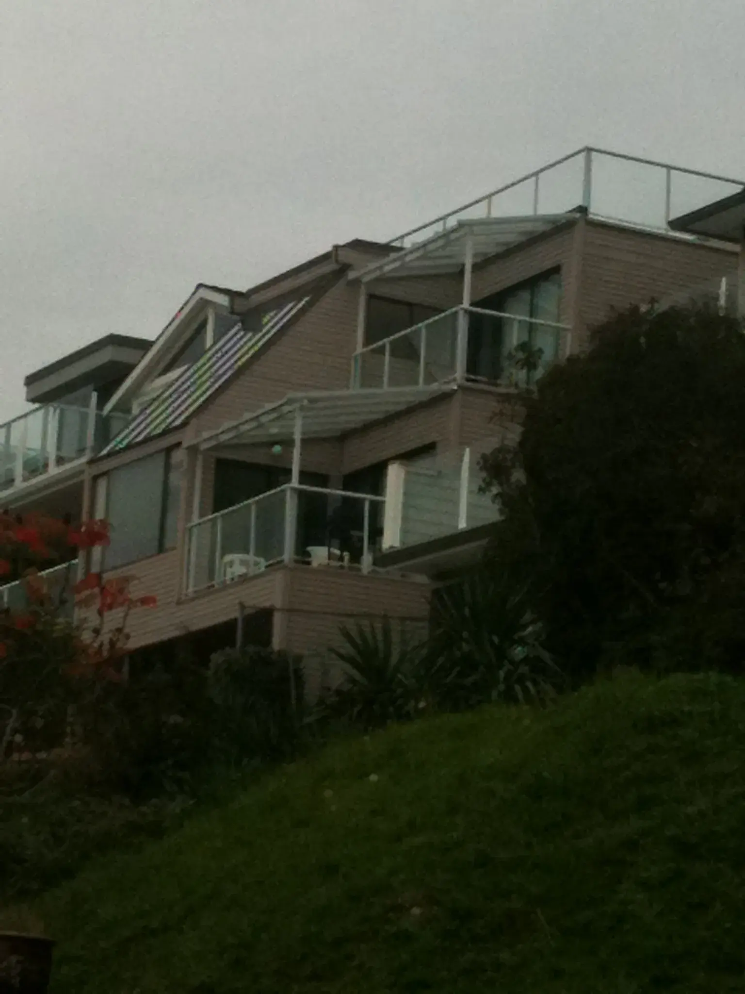 Dim evening exterior shot showing the dated taupe siding, cluttered balconies, and original roofline before renovation.