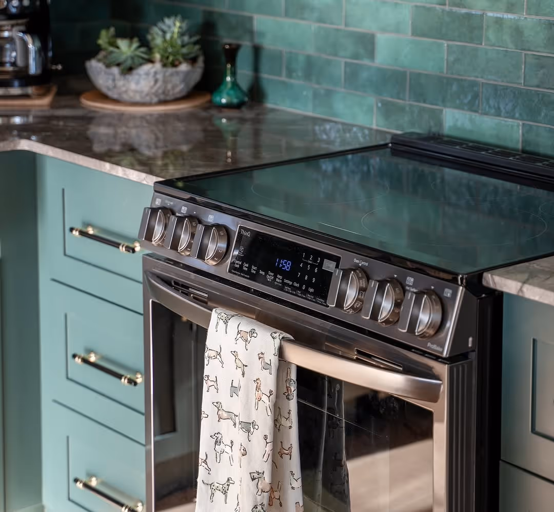 Close-up of black stainless range with digital display against green subway tile backsplash.