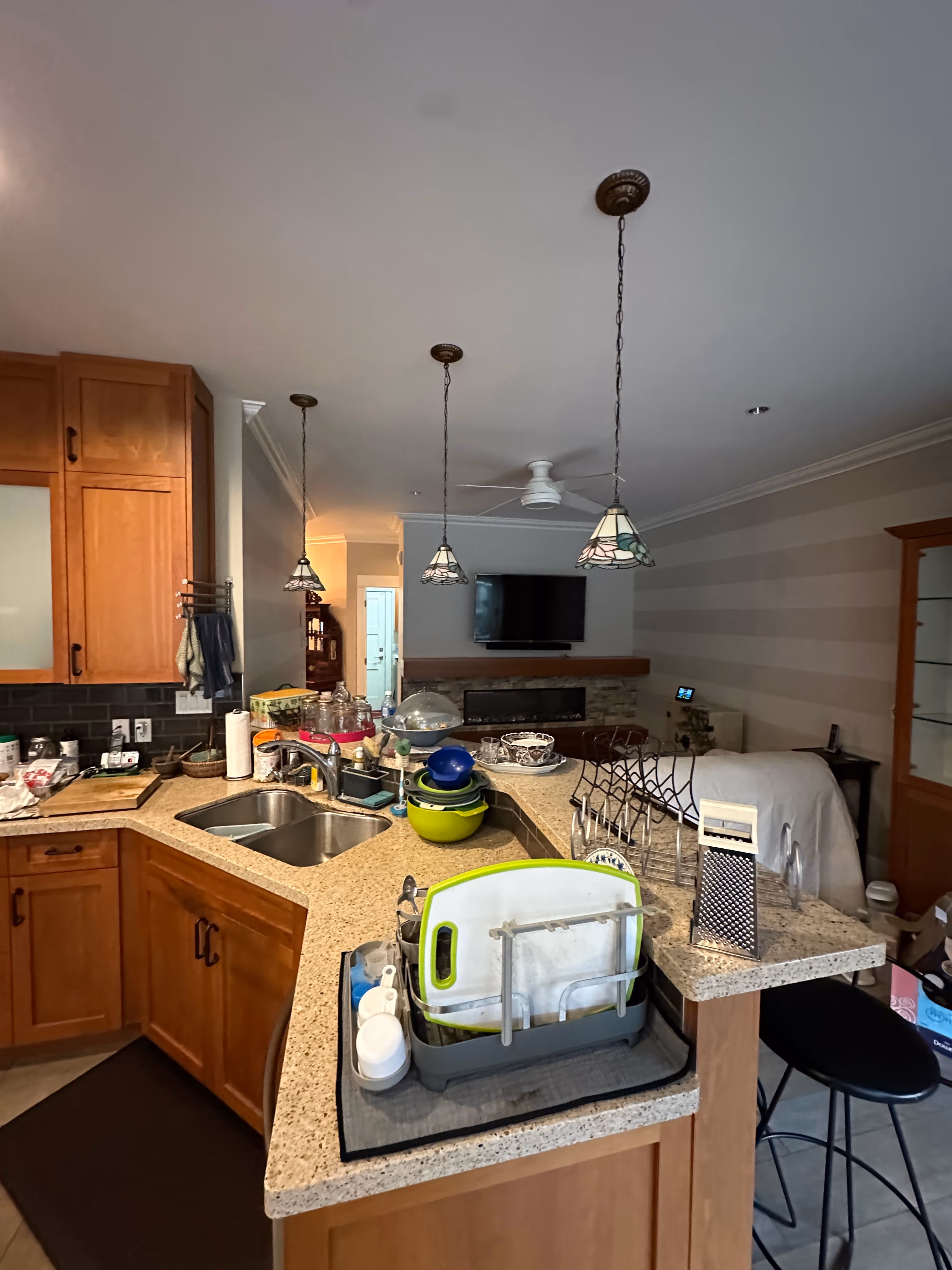 Pre-renovation kitchen island crowded with dish racks below mismatched stained-glass pendant lights.