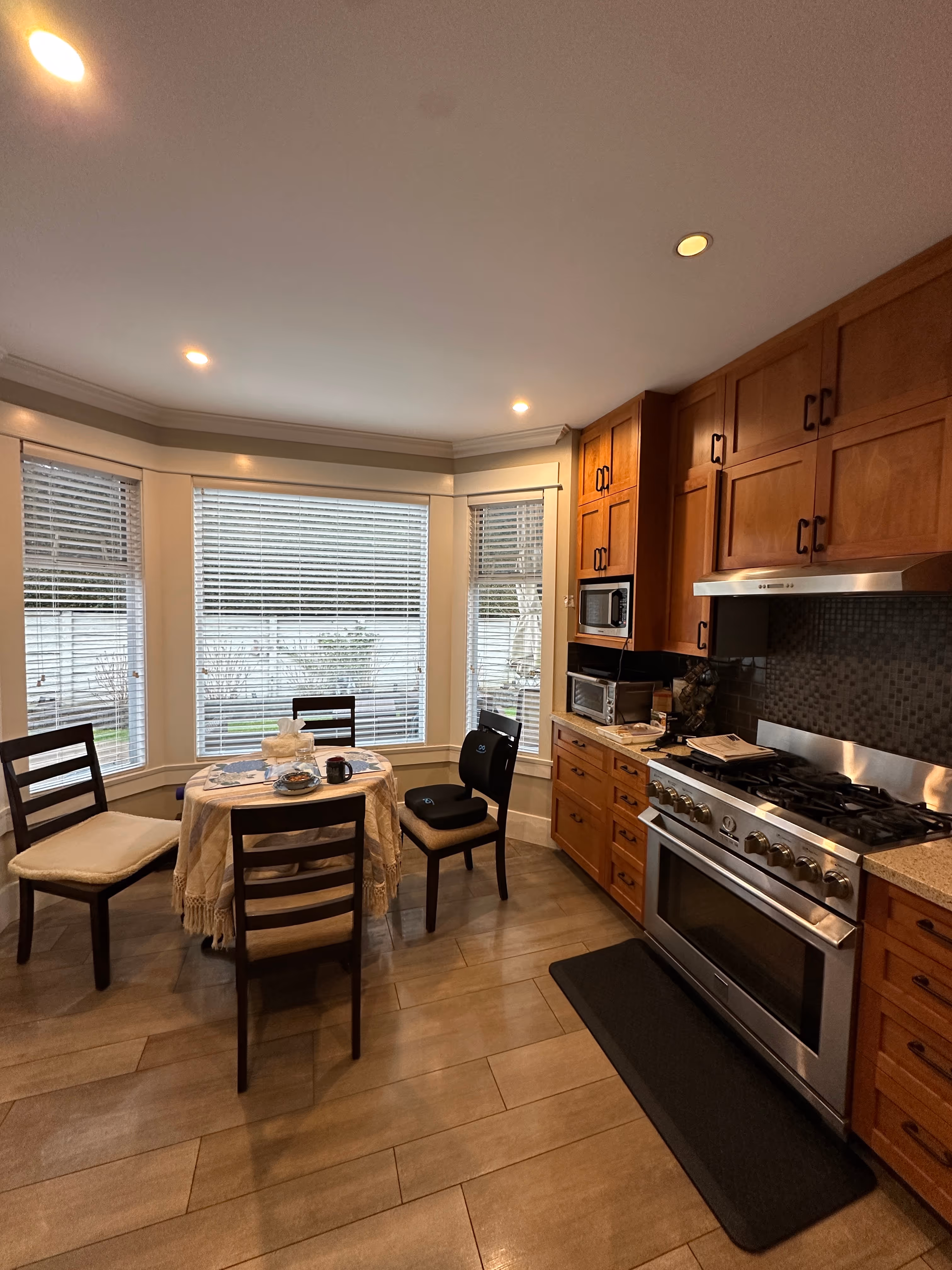 Original breakfast nook with a dark wood table, mini blinds, and worn oak cabinetry.