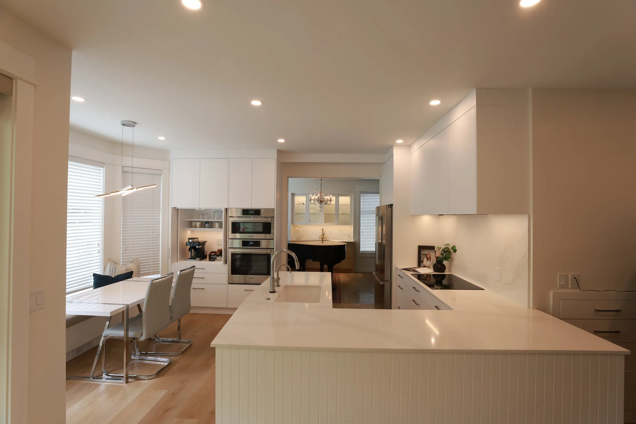 Round breakfast table by the bay window sits near the coffee station and wall ovens.