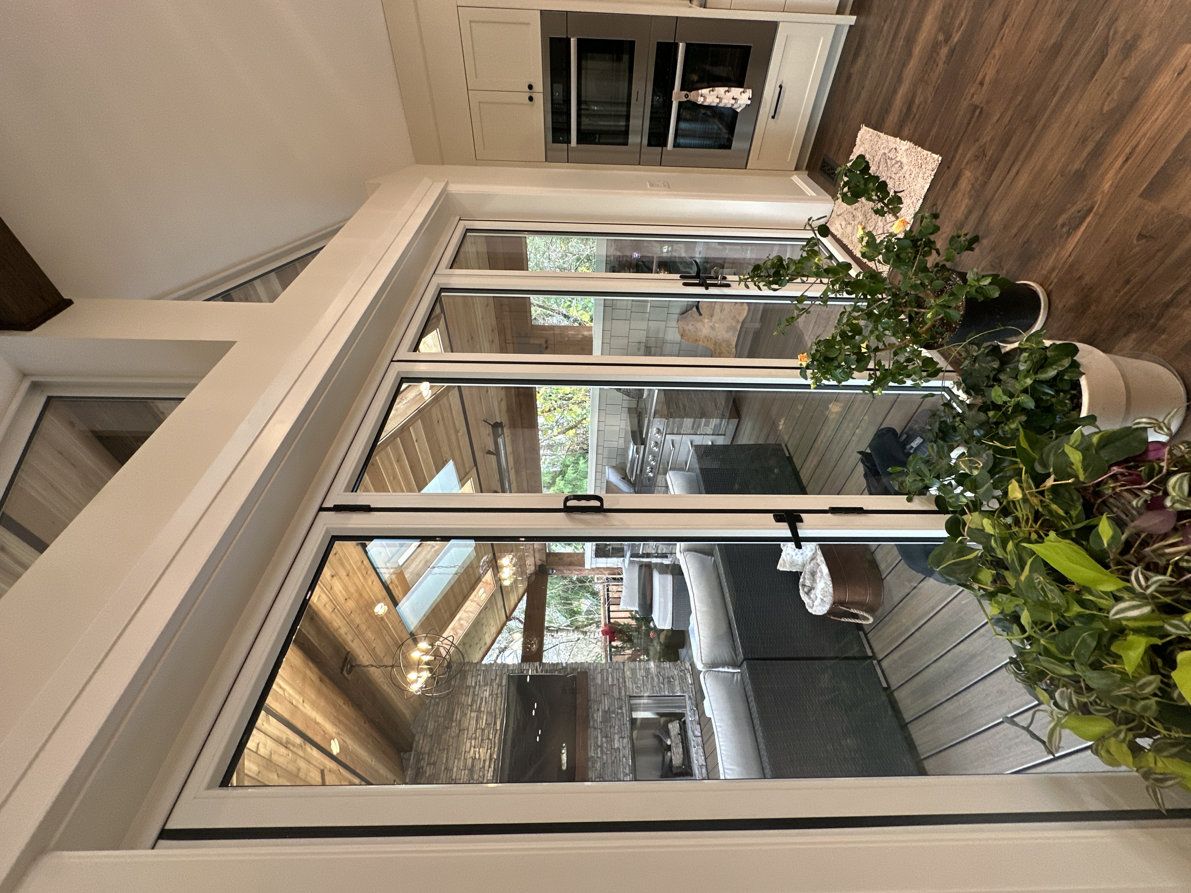 Looking down through stacked glass bifold doors onto the great room's kitchen, fireplace, and sectional below.