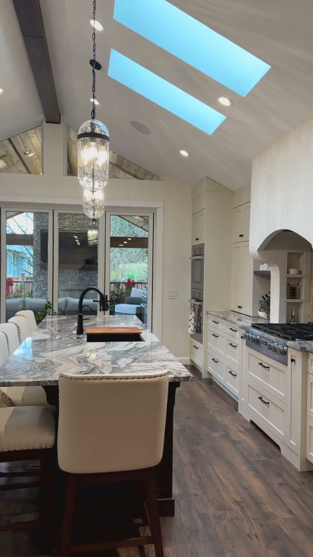 Vertical view up through twin skylights over the kitchen island seating and glass pendant lights.