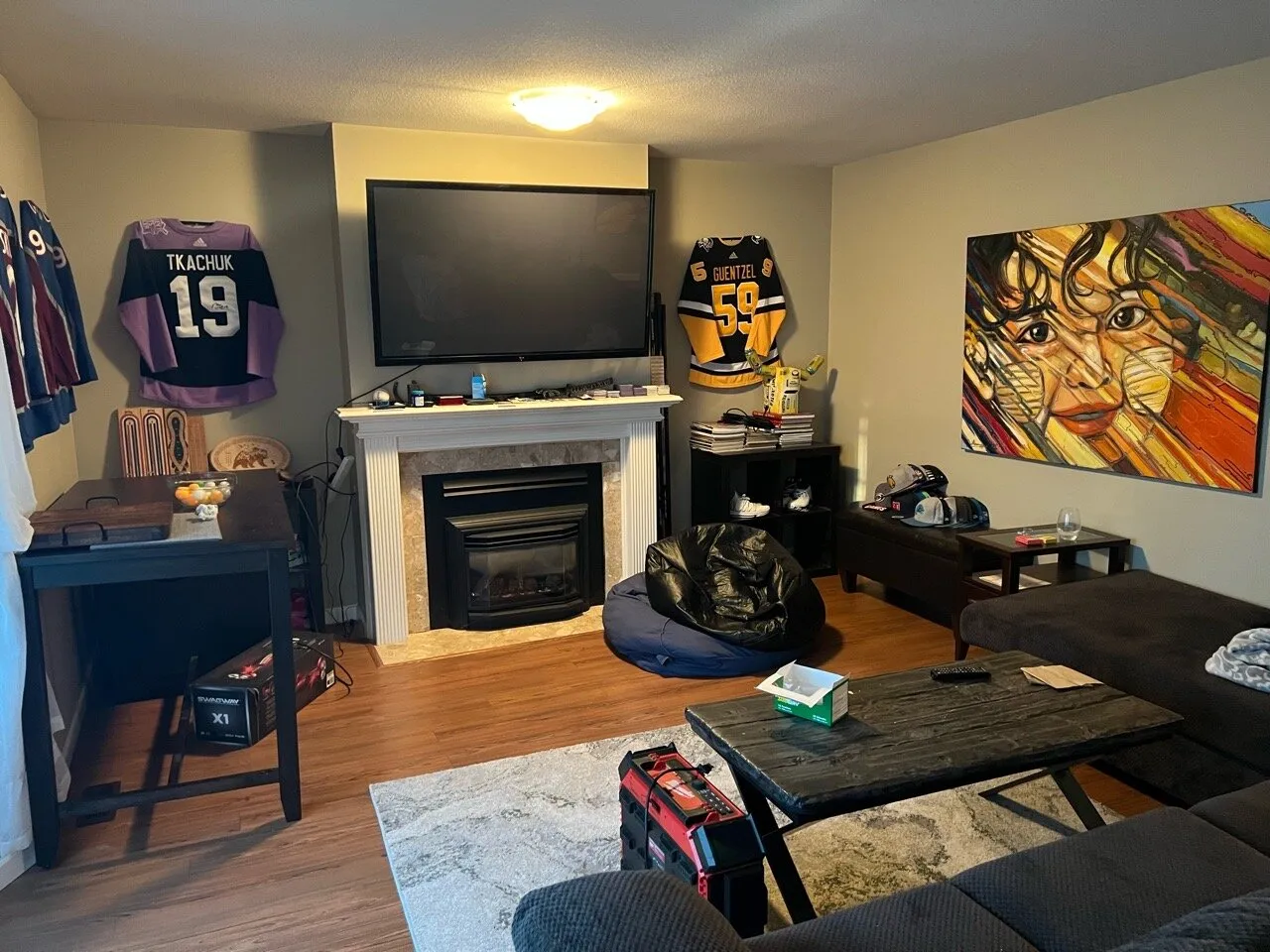 Original living room from the opposite angle, tiled fireplace, framed art, and sectional couch before renovation.