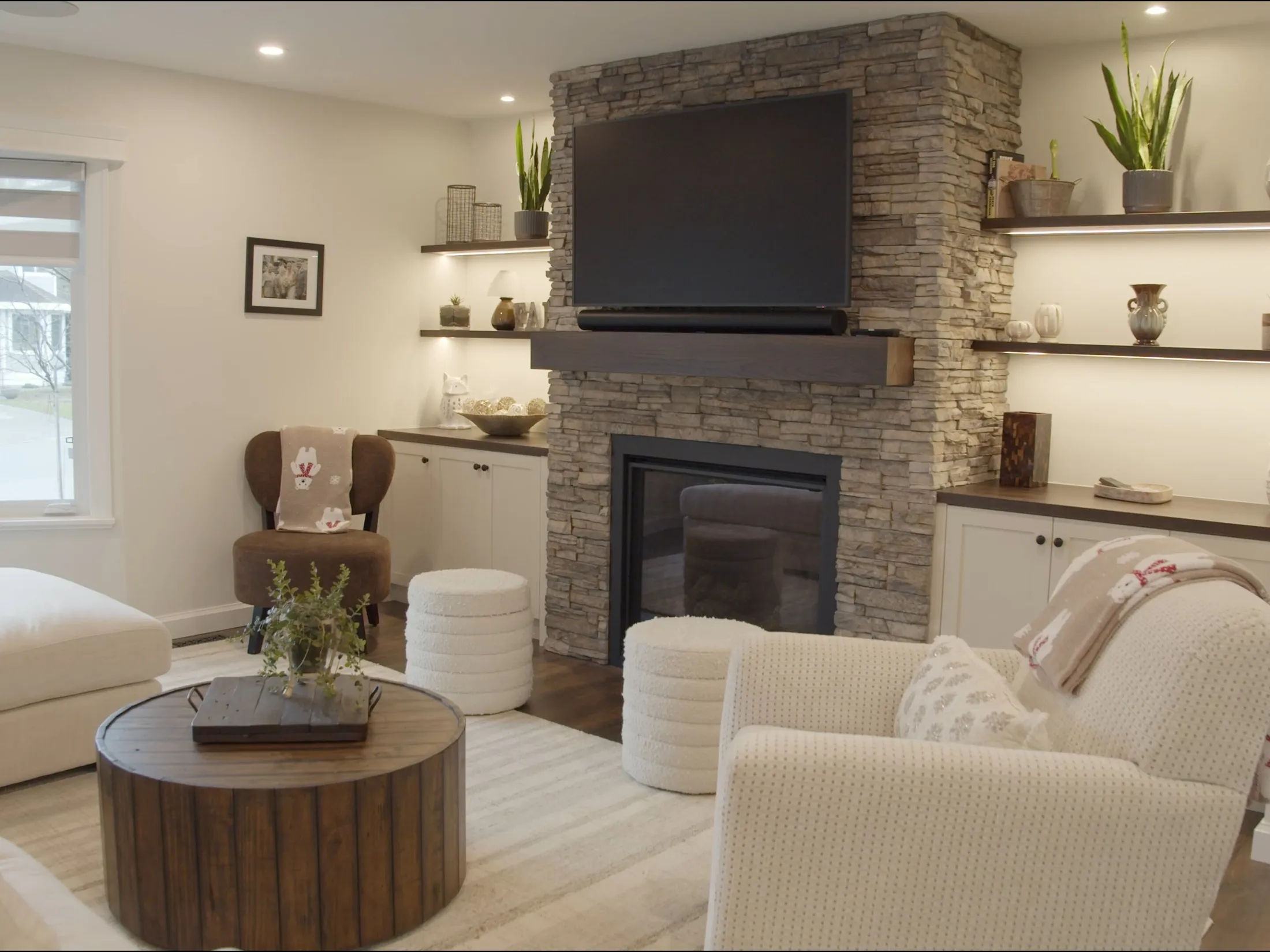 Living room fireplace with mounted TV and built-ins, holiday throw pillows and blankets styled on the seating.