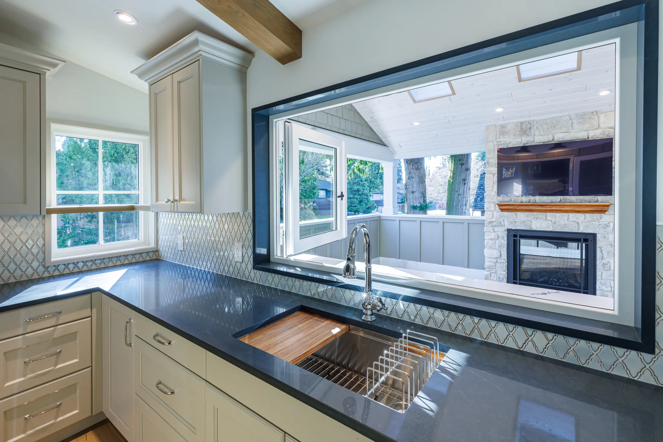 Kitchen sink pass-through window opening to the covered porch fireplace and TV beyond.