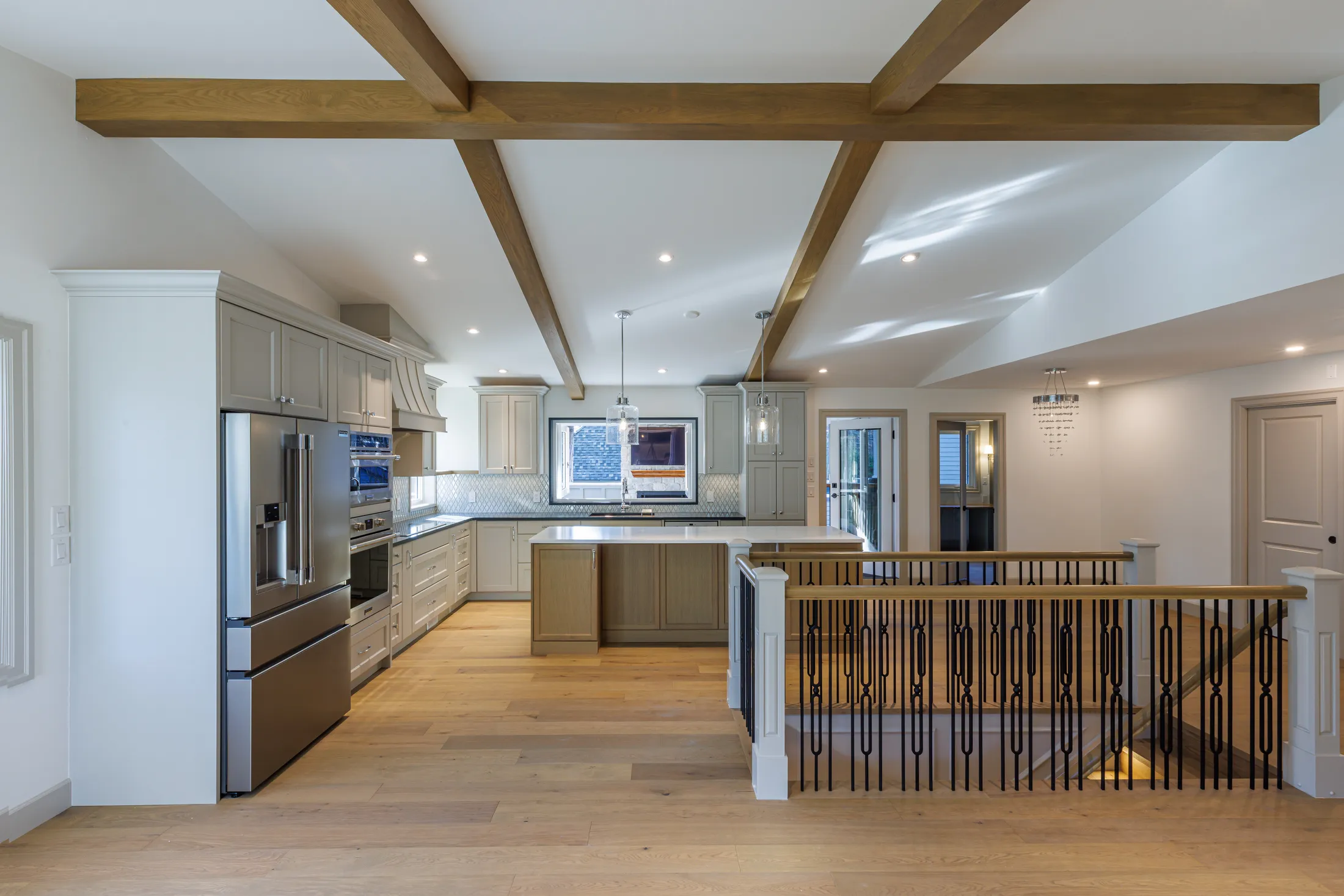 Open kitchen island with pendant lighting and wood beams, overlooking the stairwell railing below.