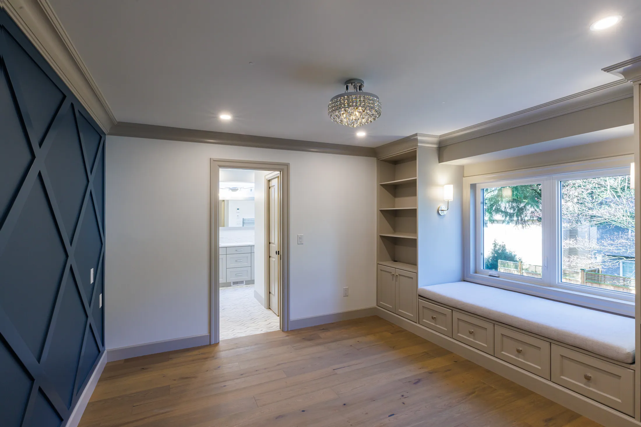 Primary bedroom with navy diamond-paneled accent wall, built-in window seat, and open shelving nook.