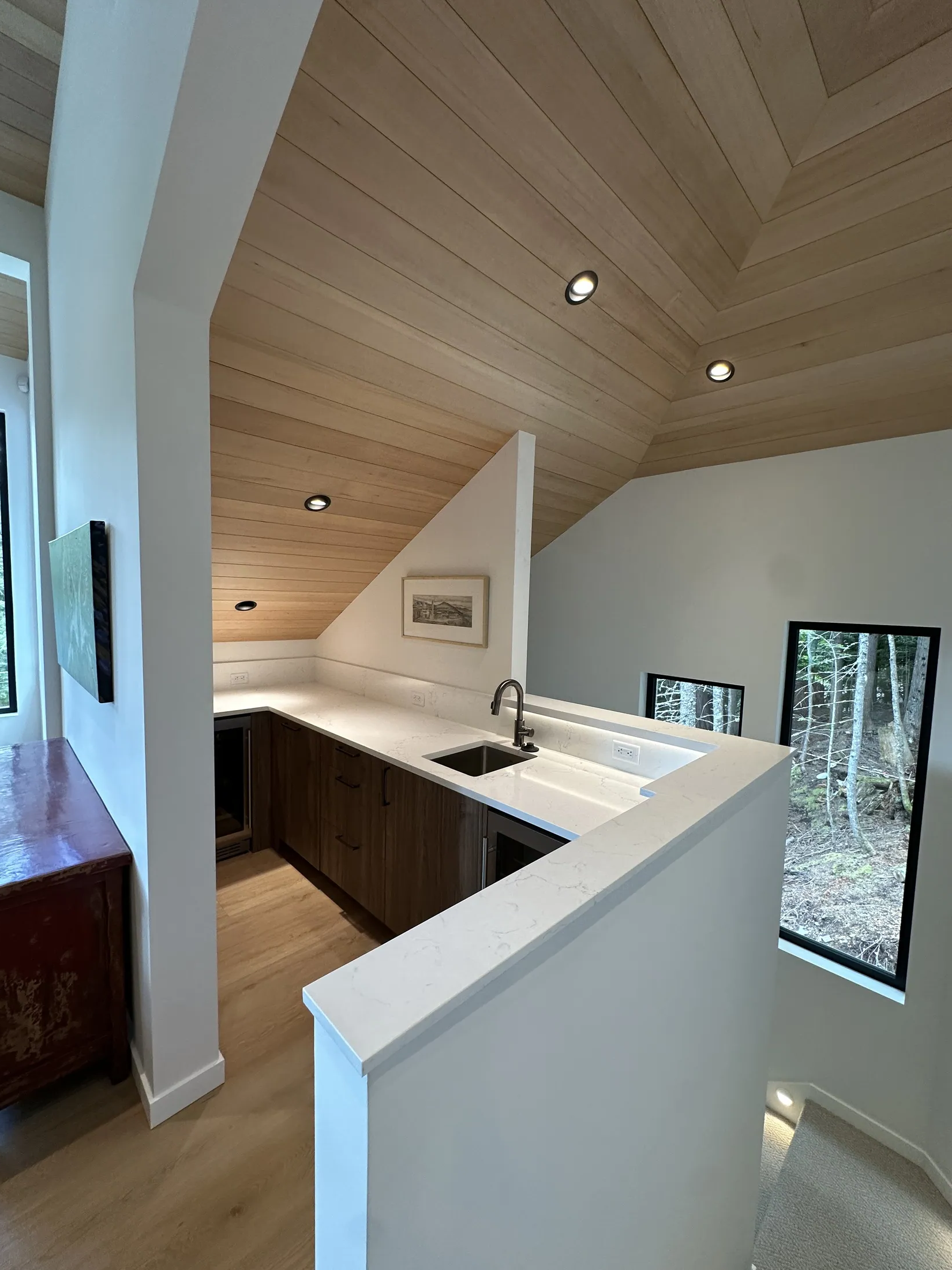 Hallway leading to a slate-blue built-in wardrobe under the roof slope, floating quartz vanity in foreground.