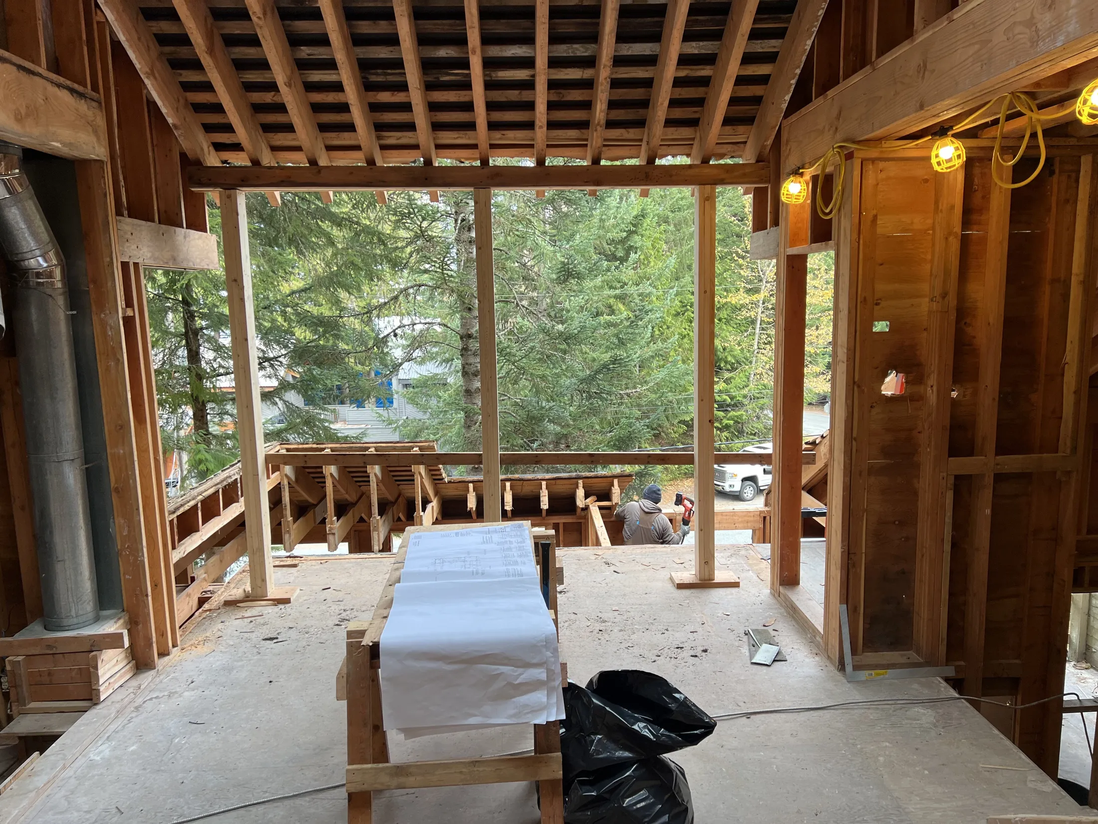 Open roof framing and unfinished walls early in the rebuild, deck structure taking shape beyond.