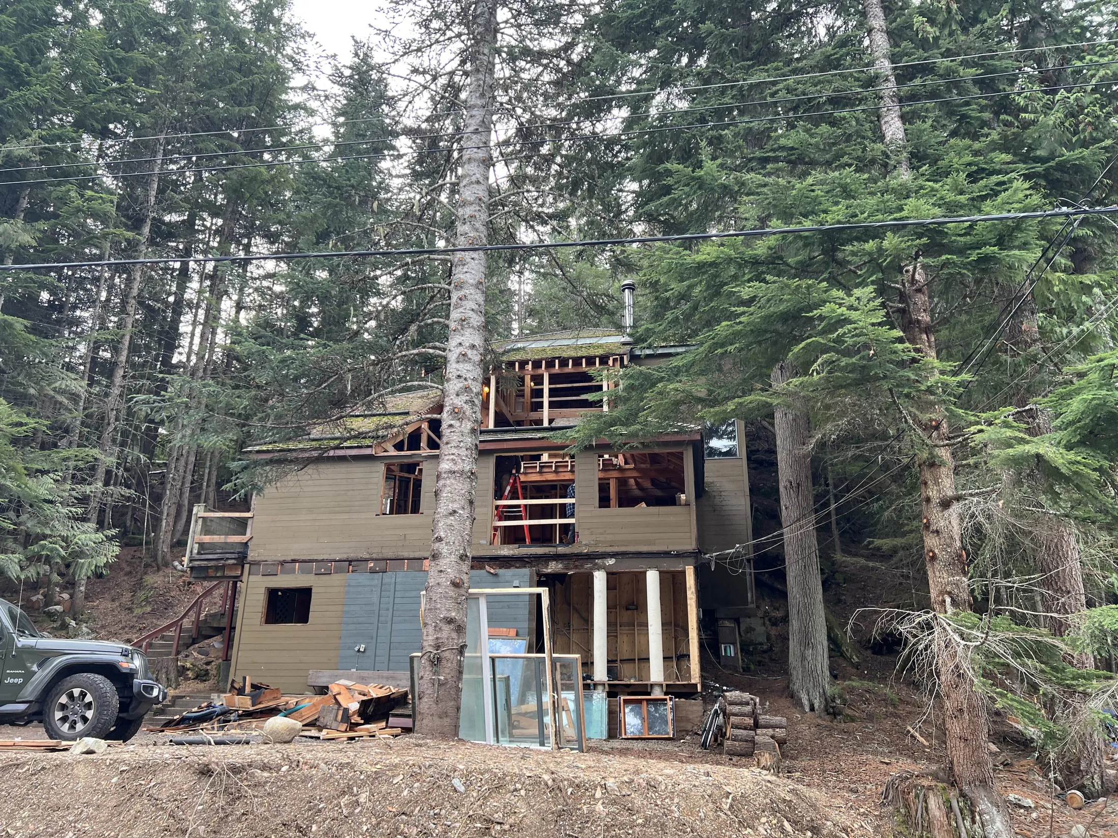 Original cabin before the rebuild: moss-covered roof, weathered siding, new framing being added on the right.